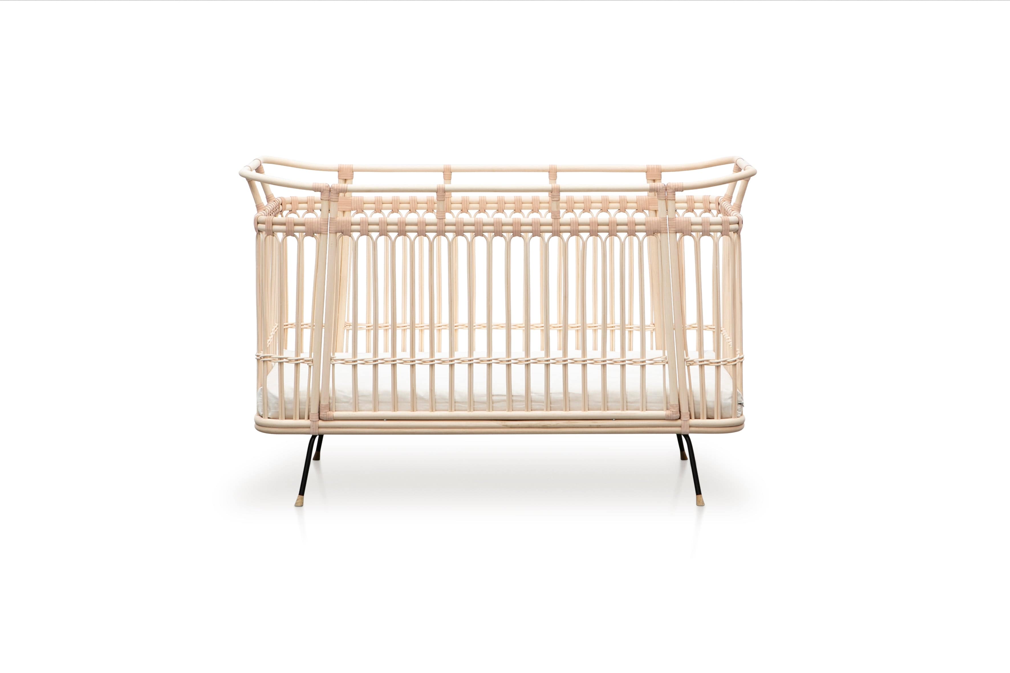 Square bed with high sides and a removable middle part on one of the longer sides. Made of beige rattan beams, connected with beige leather straps and standing on short slim black metal legs.