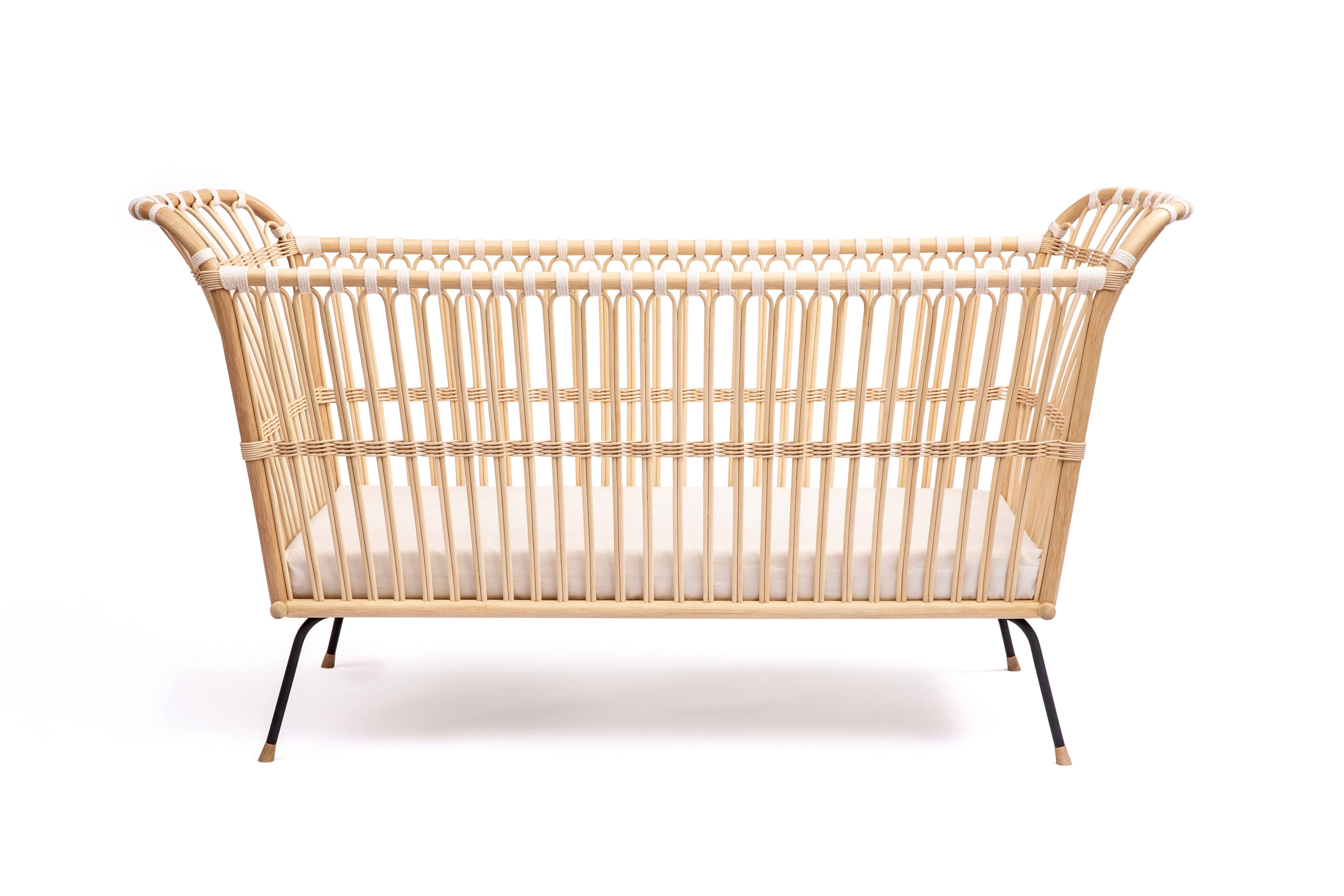 Square bed with high sides. The shorter sides of the bed are slightly higher and rounded. Made of beige rattan beams, connected with light beige cotton strings and standing on short slim black metal legs.