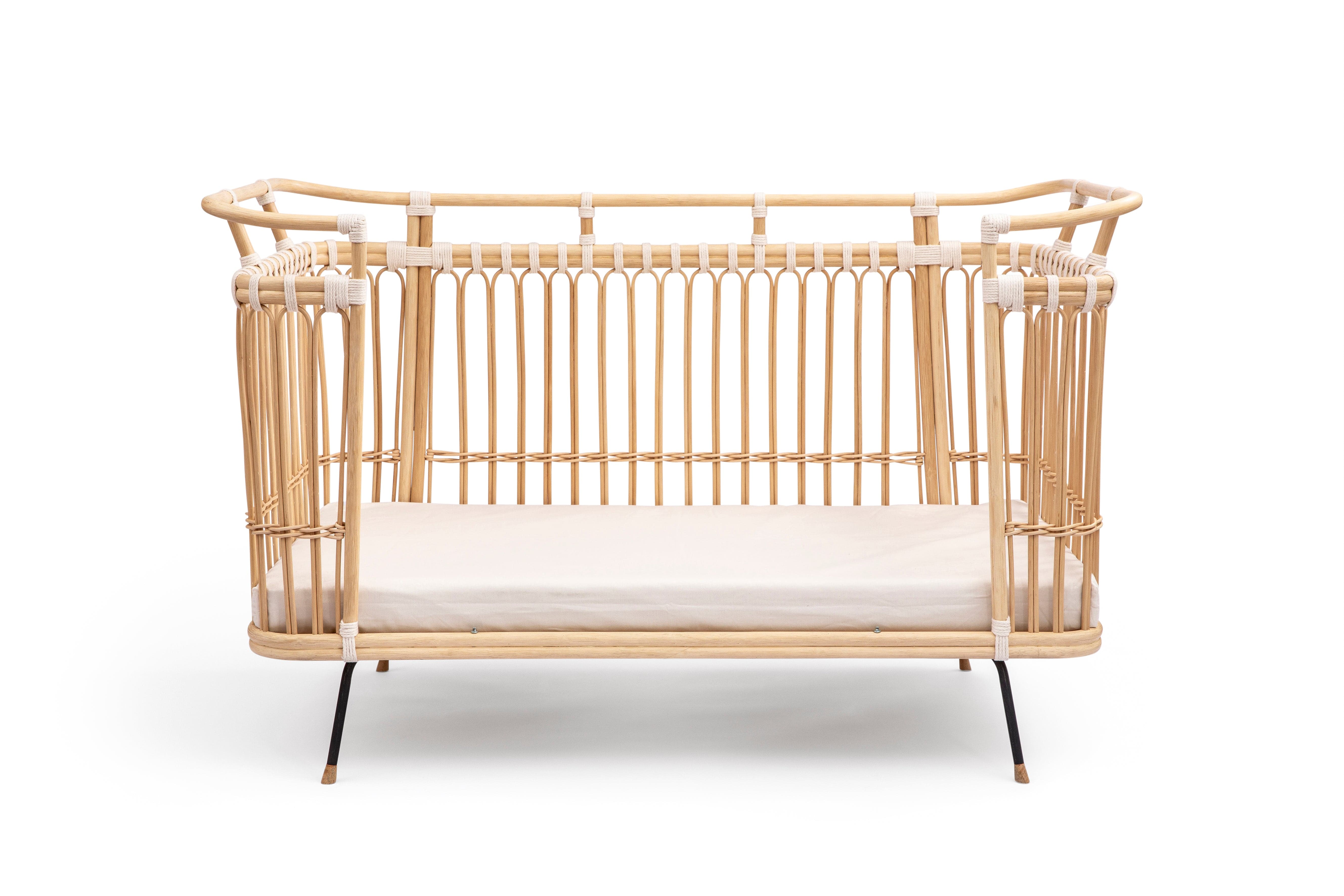 Square bed with high sides and a removable middle part on one of the longer sides. Made of beige rattan beams, connected with off-white cotton strings and standing on short slim black metal legs. 