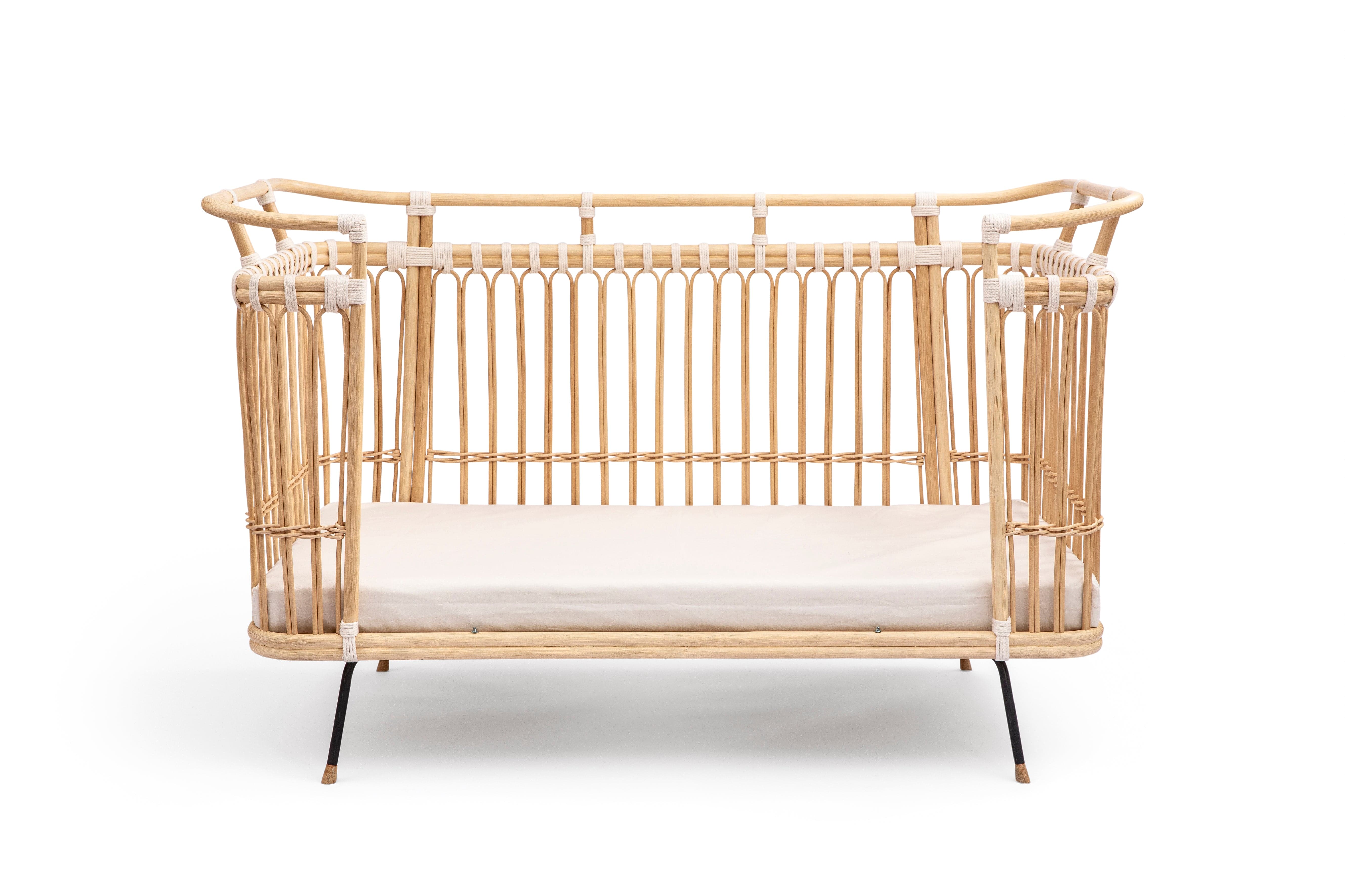 Square bed with high sides and a removable middle part on one of the longer sides. Made of beige rattan beams, connected with off-white cotton strings and standing on short slim black metal legs.