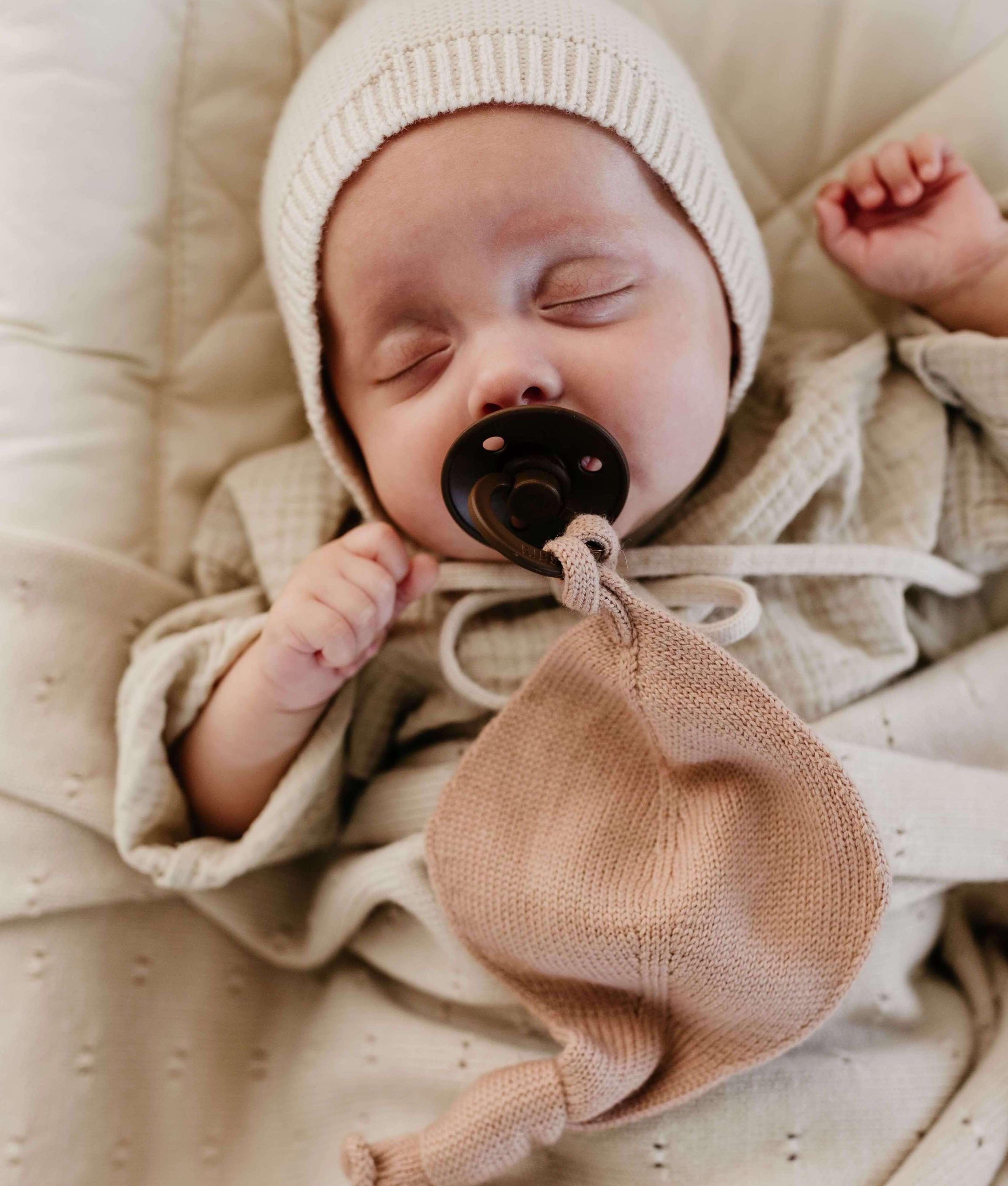Baby in beige cotton clothes, wrapped in a blanket